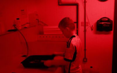 Ellis printing under the safe light in the darkroom